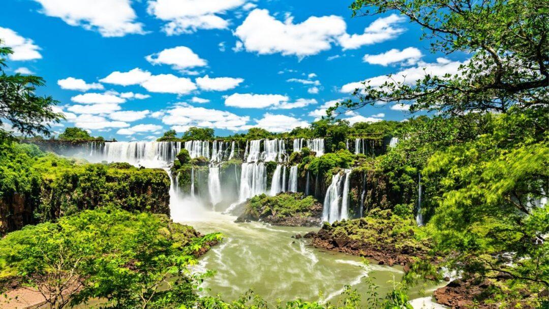 A breathtaking view of Iguazu Falls, with water cascading down from a height and creating misty clouds around it.