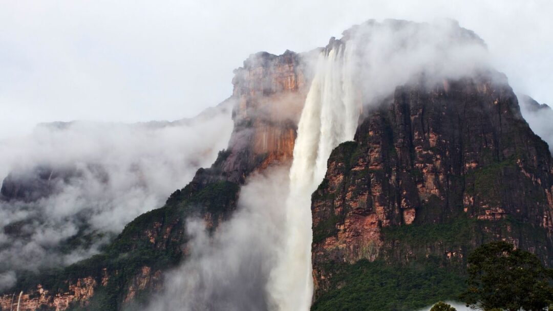 A breathtaking view of Angel Falls, Venezuela, the world's highest uninterrupted waterfall, cascading down the rugged cliffs surrounded by lush greenery. Top 10 Spectacular Waterfalls to Visit.