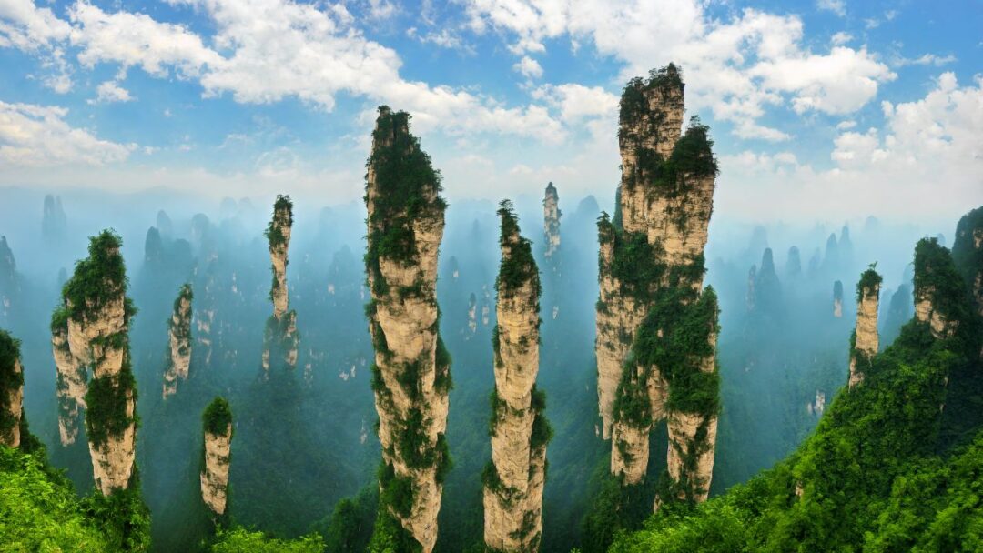 A breathtaking view of Zhangjiajie National Park in China, with towering sandstone pillars rising majestically from lush green forests. 10 Most Beautiful National Parks Around the World.